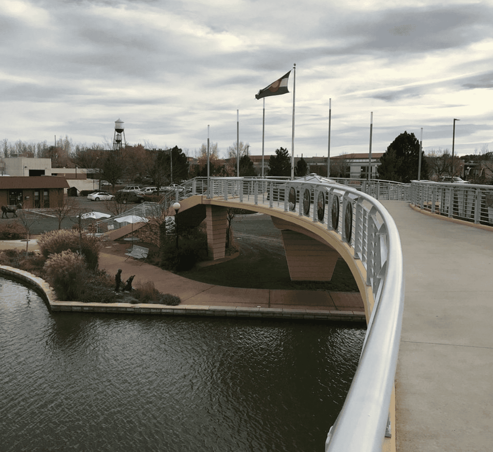 Colorful pedestrian bridge over a pond at QuestForDirections park, offering scenic views and outdoor walking space.