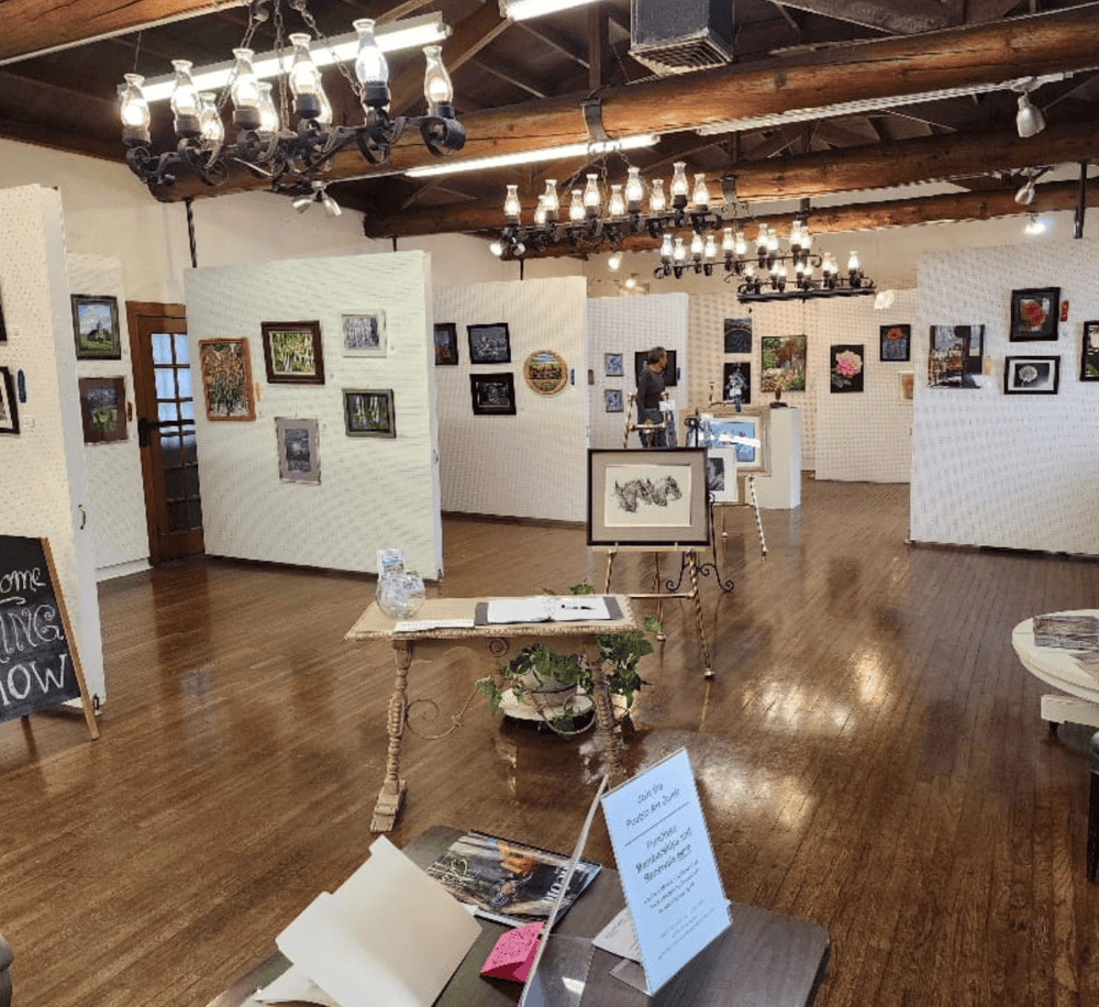Elegant art gallery featuring diverse paintings and framed artwork in a rustic, well-lit exhibition space.