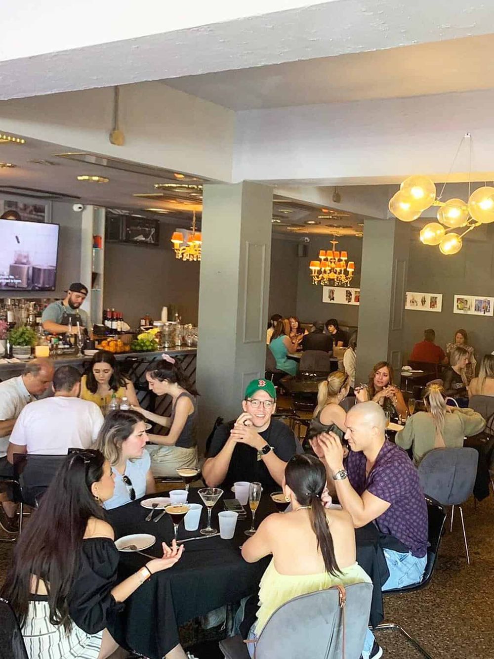 Vibrant restaurant scene with diverse guests enjoying cocktails and conversations in a stylish dining setting.