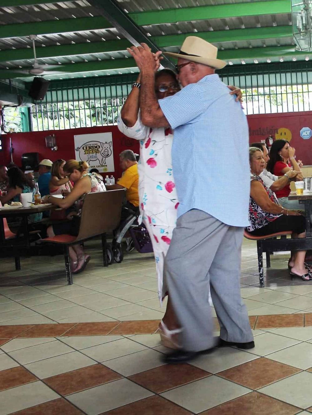 Joyful elderly couple dancing at a lively restaurant, showcasing vibrant social interactions and fun activities for seniors.