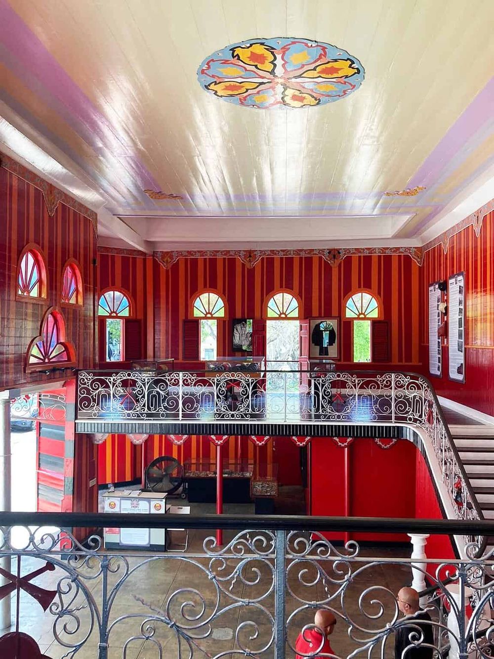 Colorful vintage interior with ornate iron railings and vibrant red striped walls, perfect for unique event or gathering spaces.