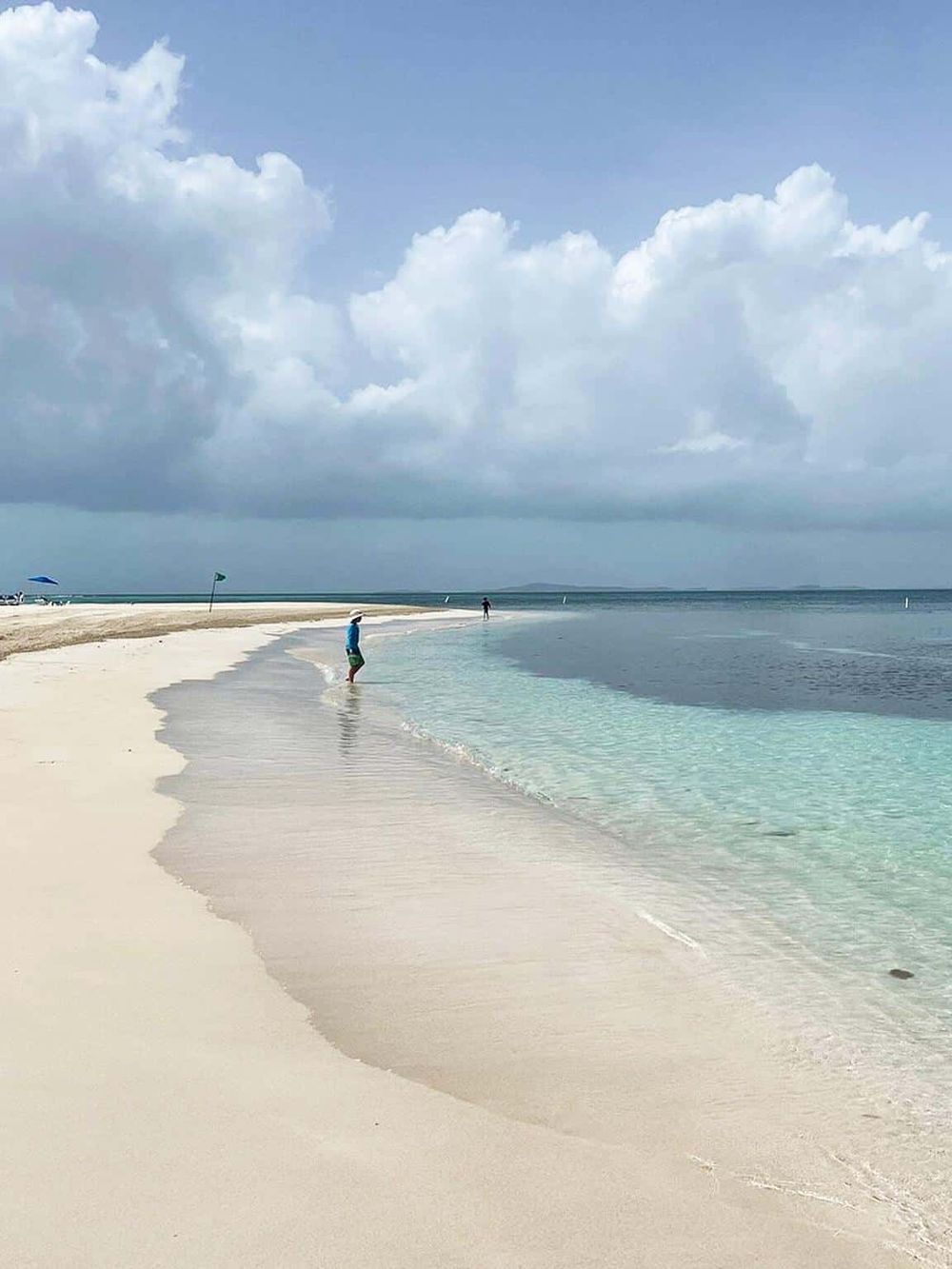 Serene beach with white sand, clear water, and a cloudy sky, perfect for relaxation and seaside activities.