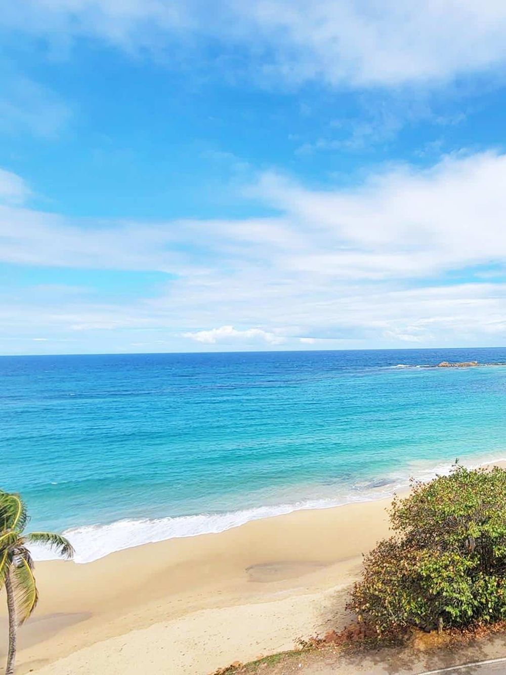Stunning beach scene with turquoise waters, white sand, blue sky, and lush greenery. Perfect coastal getaway for relaxation and travel planning.