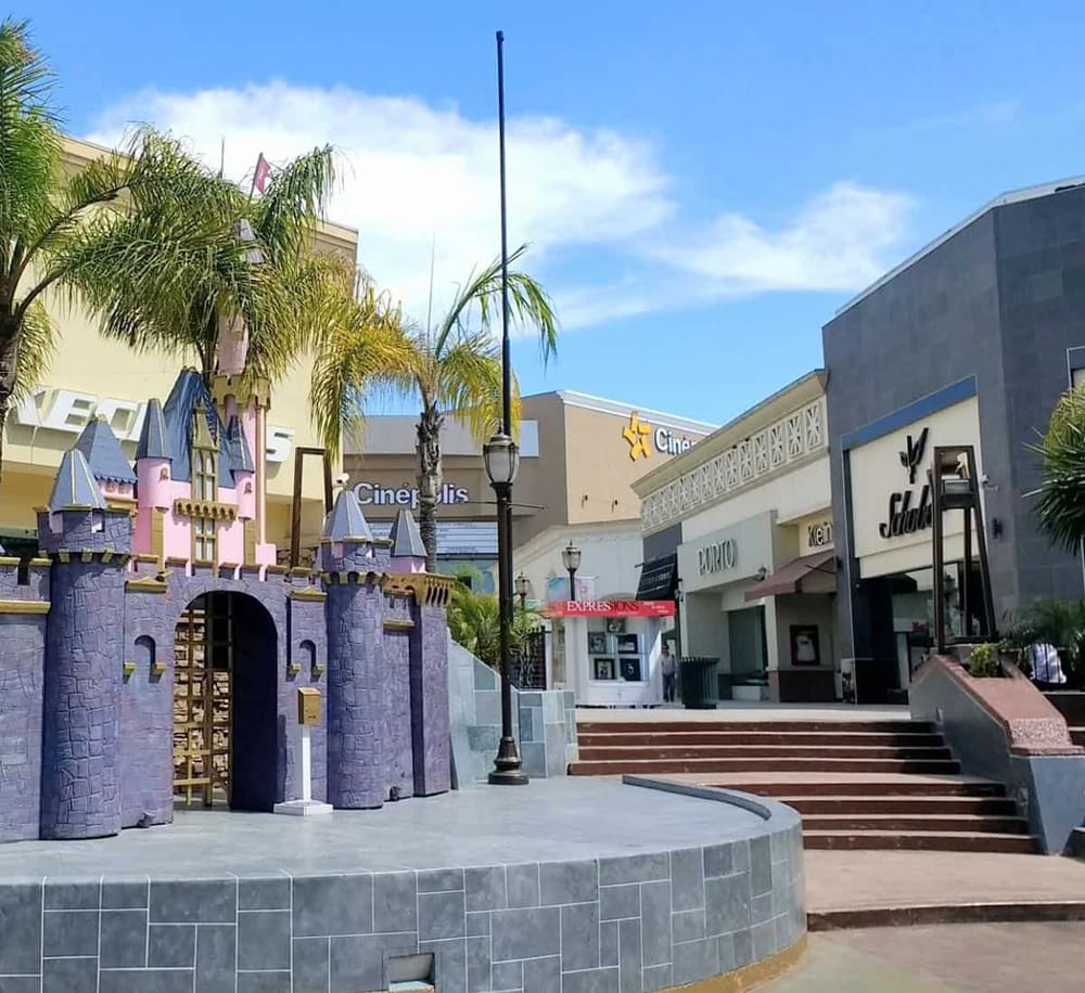 Colorful castle fountain at outdoor shopping mall with popular stores and palm trees in California.