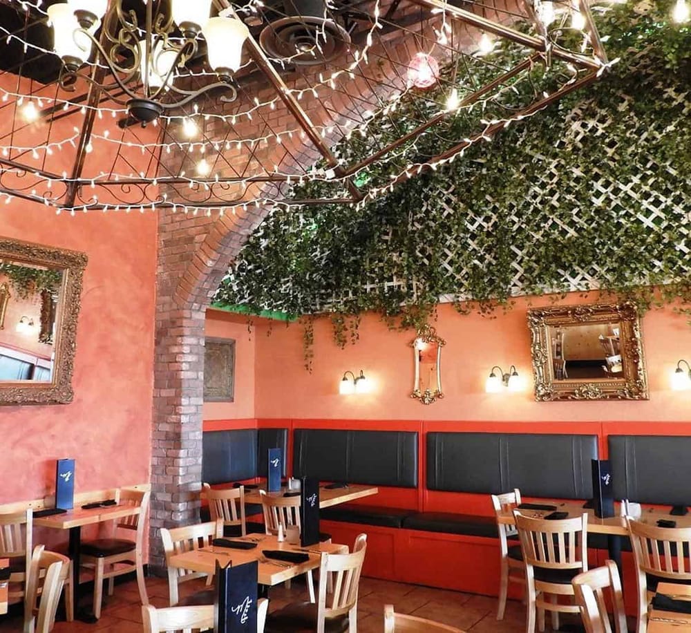 Warm dress restaurant interior with fairy lights and greenery ceiling decor.