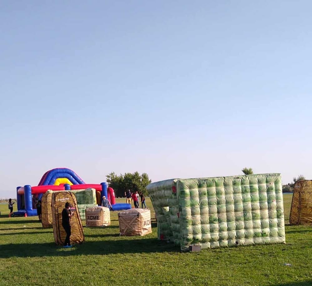 Colorful outdoor inflatable attractions on grassy field for family fun and entertainment.