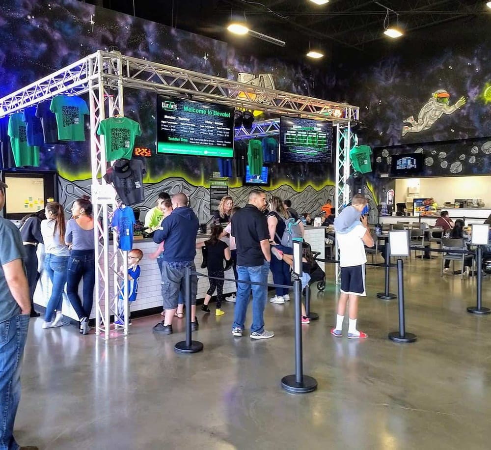 Bright indoor arcade with space-themed decor, screening area, and people waiting in line at Quest for Directions.