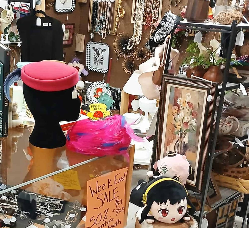 Colorful thrift store with vintage decor, jewelry, artwork, and sale signs.