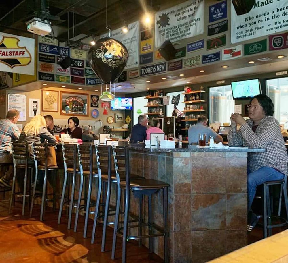 Cozy pub interior with diverse patrons, vintage signs, flat-screen TVs, and a welcoming atmosphere. Perfect for casual dining and drinks.