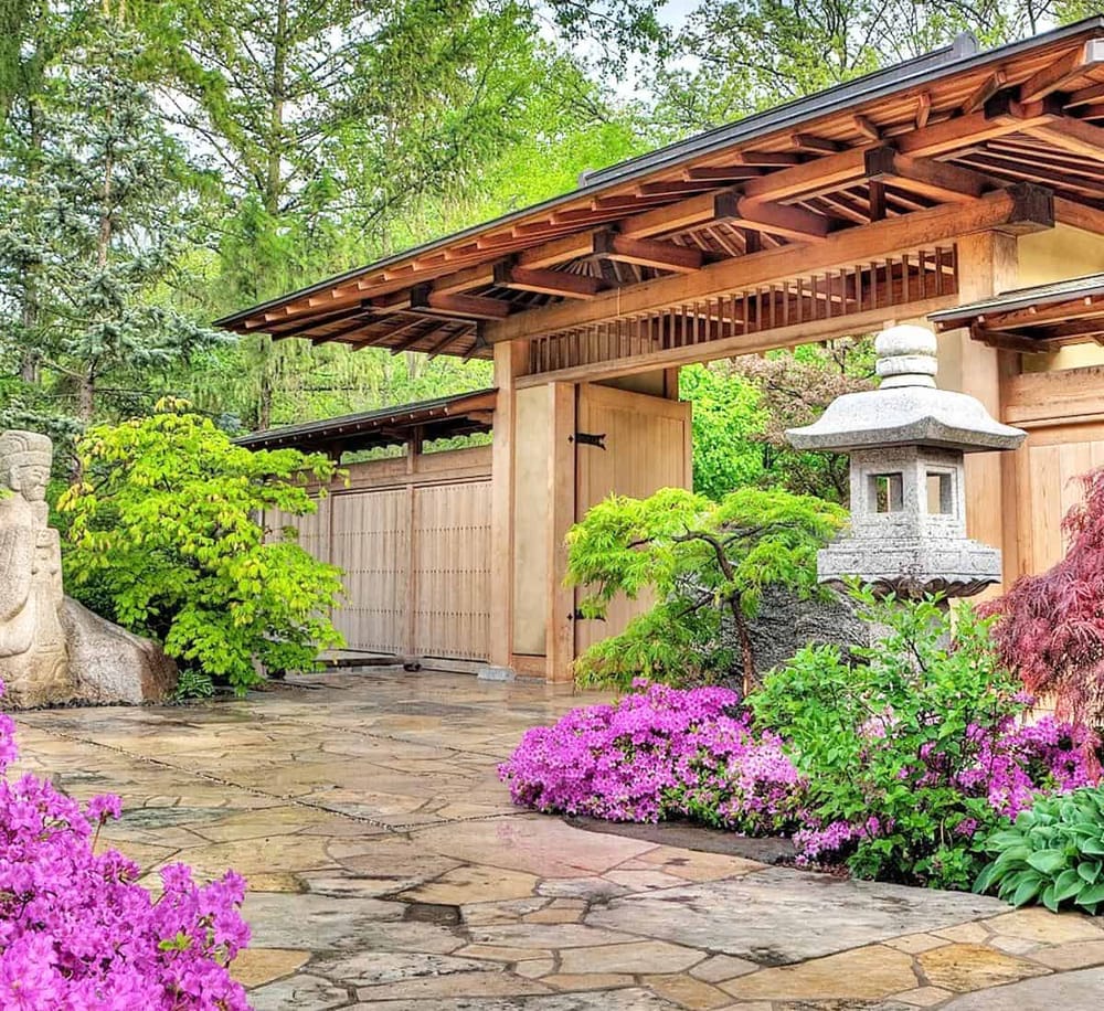 Serene Japanese garden entrance with traditional wooden gate and stone lanterns, perfect for guiding visitors.