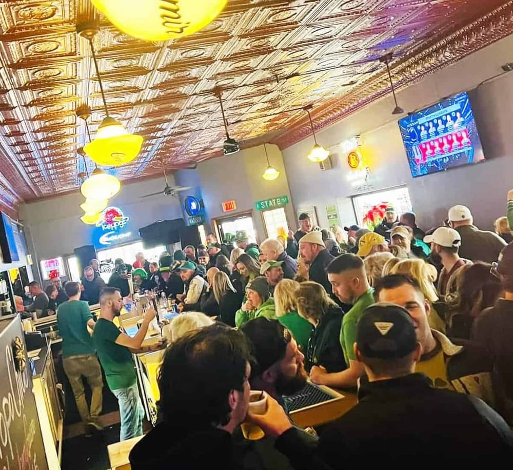 Bustling bar filled with people enjoying drinks in a lively, trendy environment.