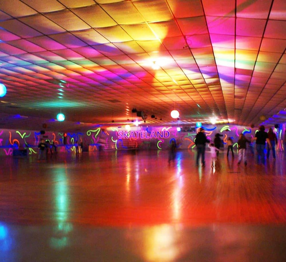 Colorful roller skating rink with vibrant neon lights and people enjoying skating at Skateland.
