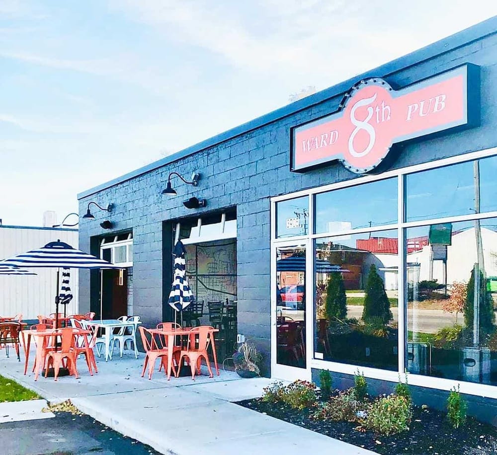 Charming outdoor seating at Ward 8th Pub with vibrant pink and black exterior. Perfect spot for casual dining and drinks.