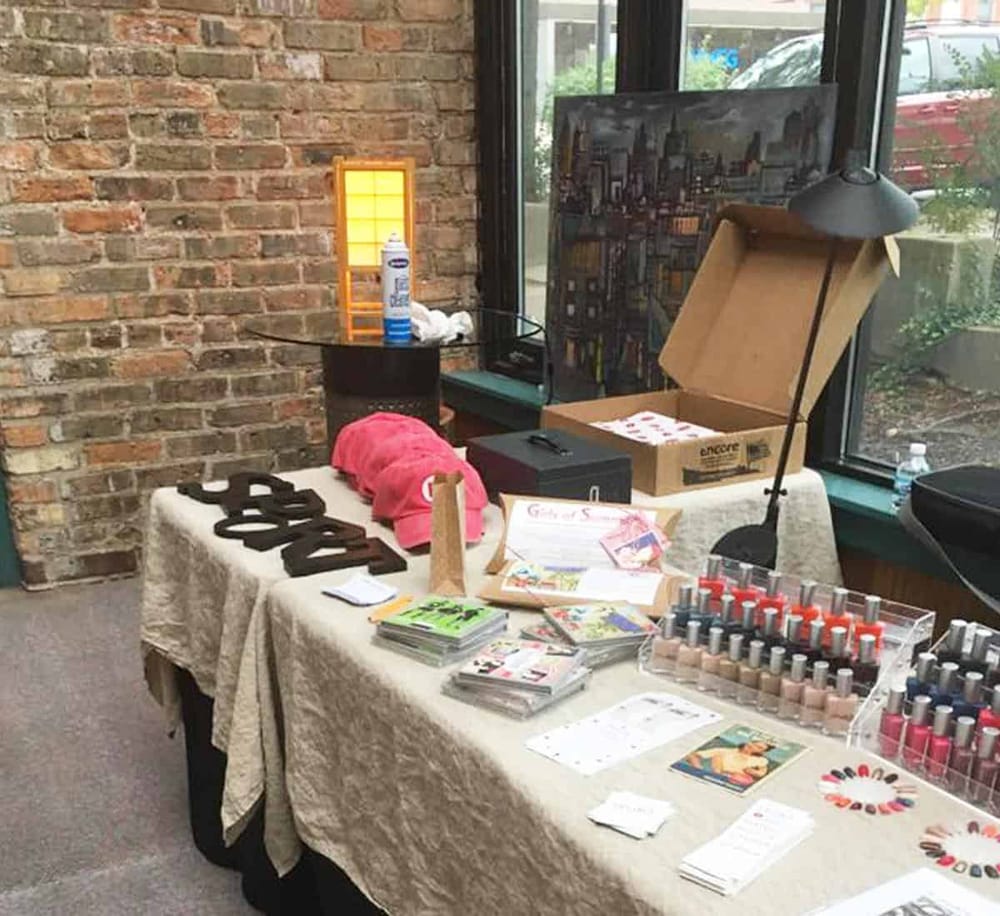 Colorful event display table showcasing promotional materials, nail polish, and gift items at QuestForDirections location.