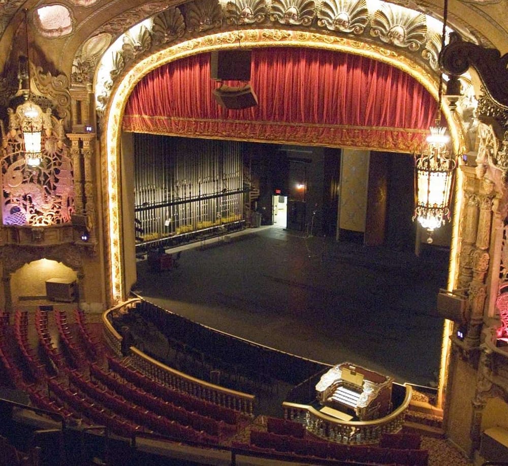 Ornate theater stage with red velvet curtains at QuestForDirections venue.