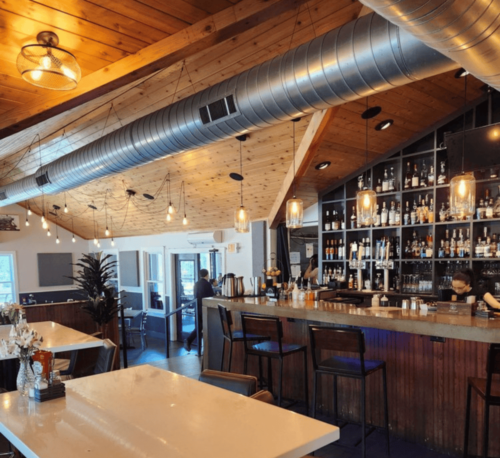 Cozy modern bar with wood ceiling, ambient lighting, and extensive liquor display for a trendy dining experience.