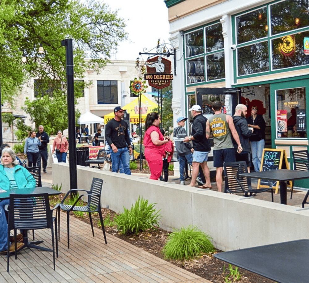 Outdoor dining scene with people ordering pizza at Quest for Directions restaurant.