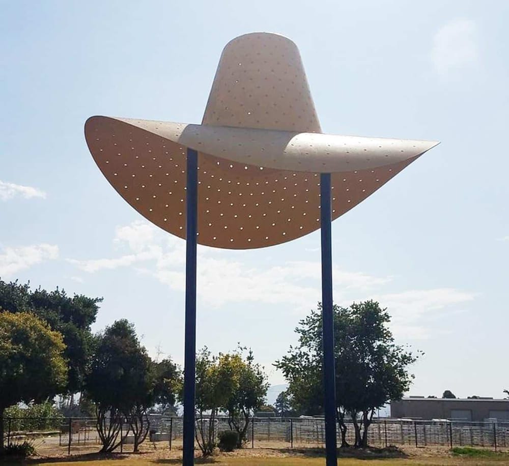 Colorful big cowboy hat sculpture in an outdoor park, symbolizing Western culture and adventure.