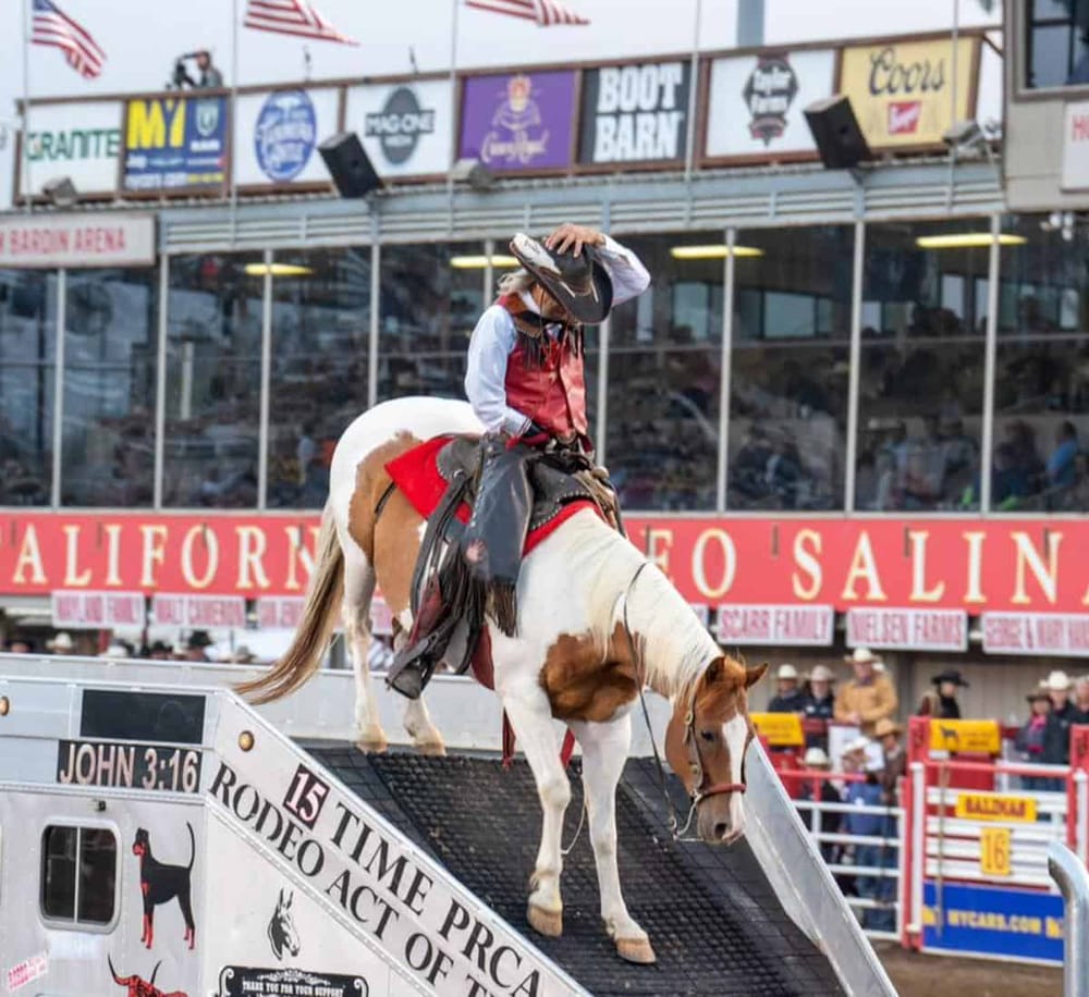 Rodeo cowboy balancing on horse platform at California fair event for entertainment and rodeo sports.