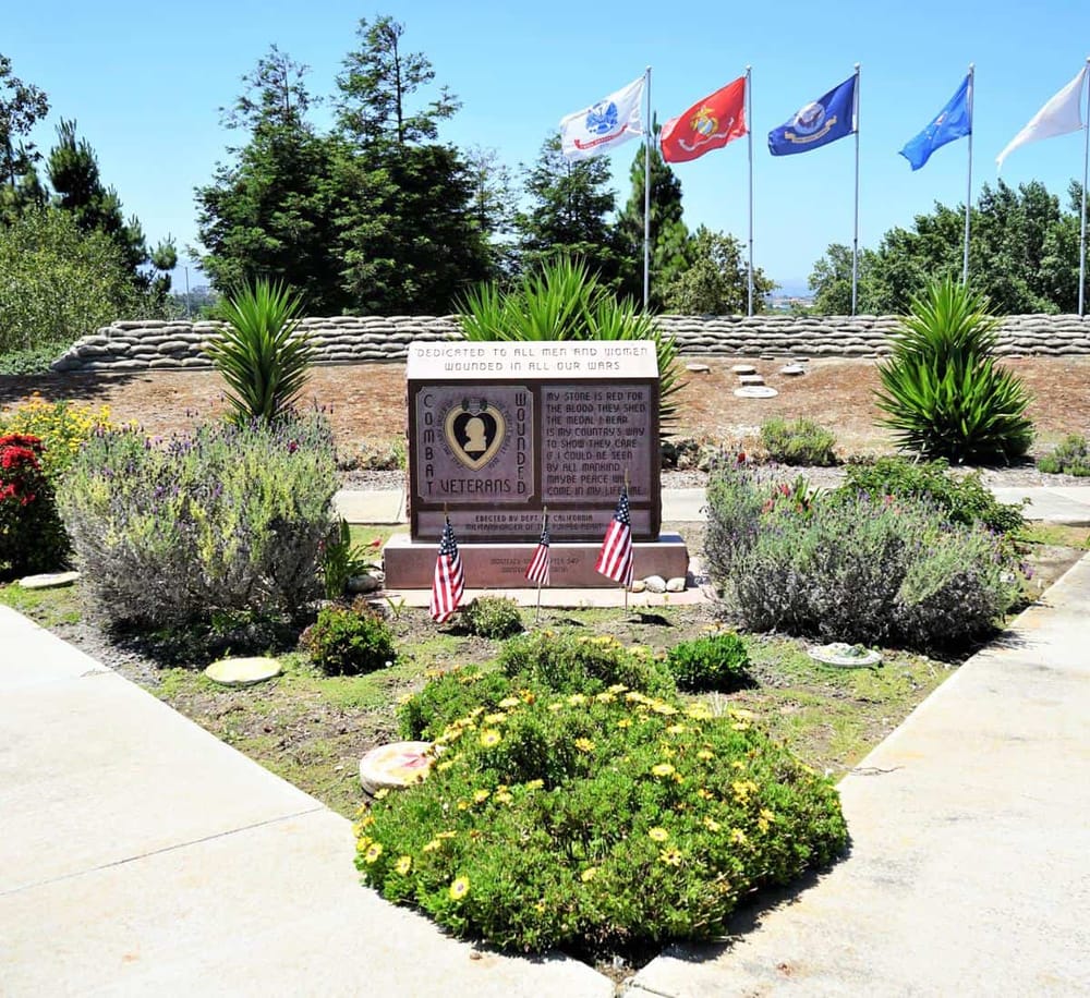 Honoring veterans memorial with flags, flowers, and patriotic symbols at QuestForDirections site.