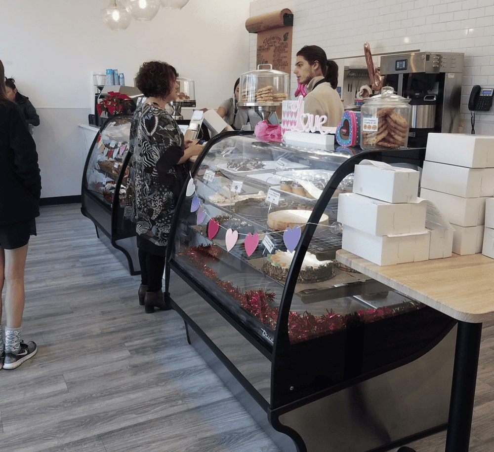 Delicious desserts at a cozy bakery counter, with customers ordering and enjoying sweet treats.