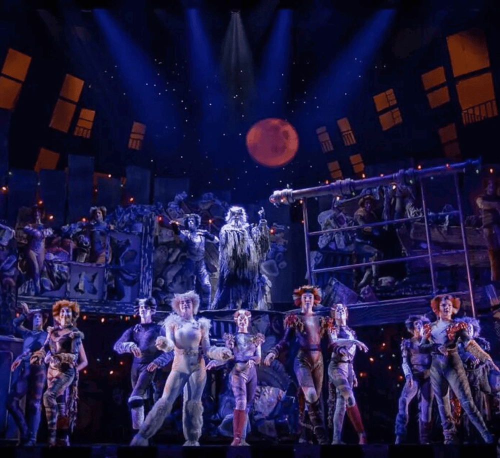 Vibrant theatrical scene with elaborate costumes, starry backdrop, and moon, showcasing a captivating performance.