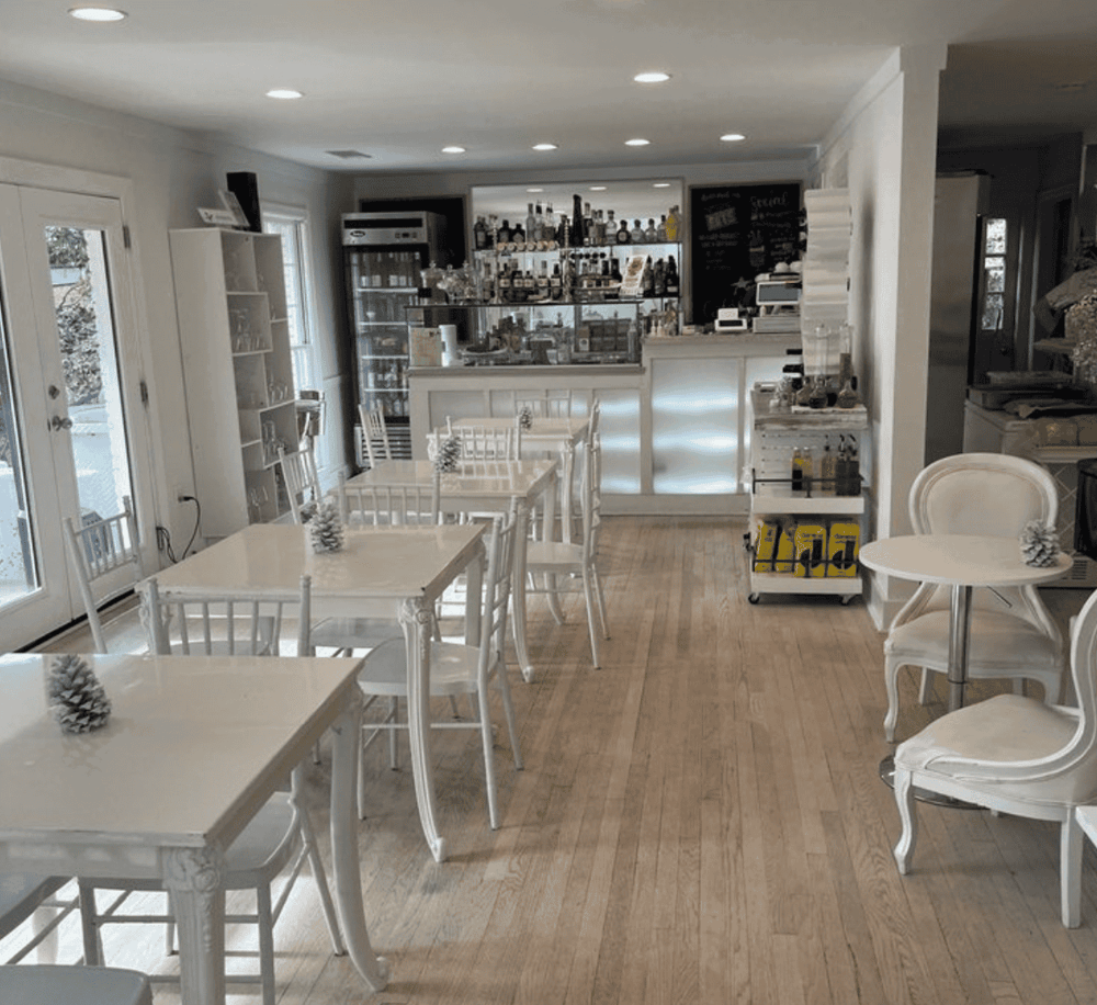 Cozy cafe interior with white furniture and a bar, perfect for relaxing and enjoying delicious foods and drinks.