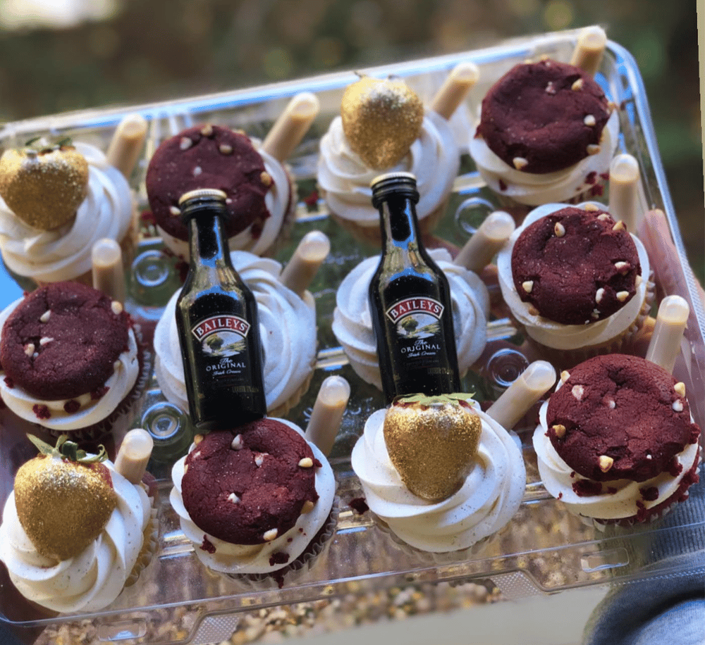 Delicious cupcakes with Baileys Irish Cream mini bottles and gold heart toppers, perfect for dessert or celebration.