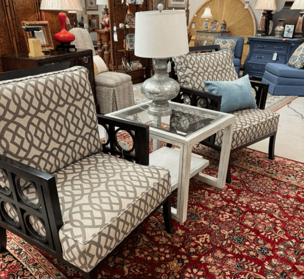 Elegant living room furniture display with patterned chairs, glass-top table, and decorative lamps for home decor.