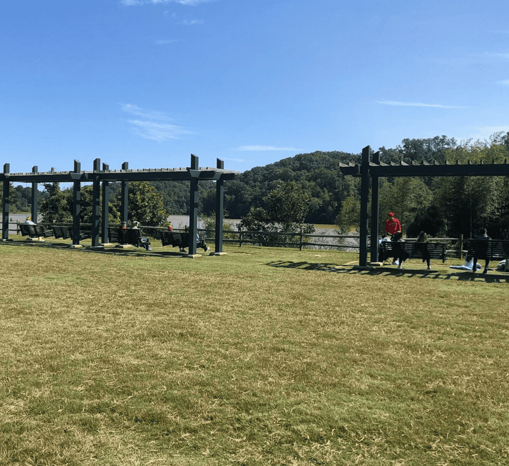 Open outdoor park with benches, pergolas, and scenic river views, perfect for leisure and exploring nature.