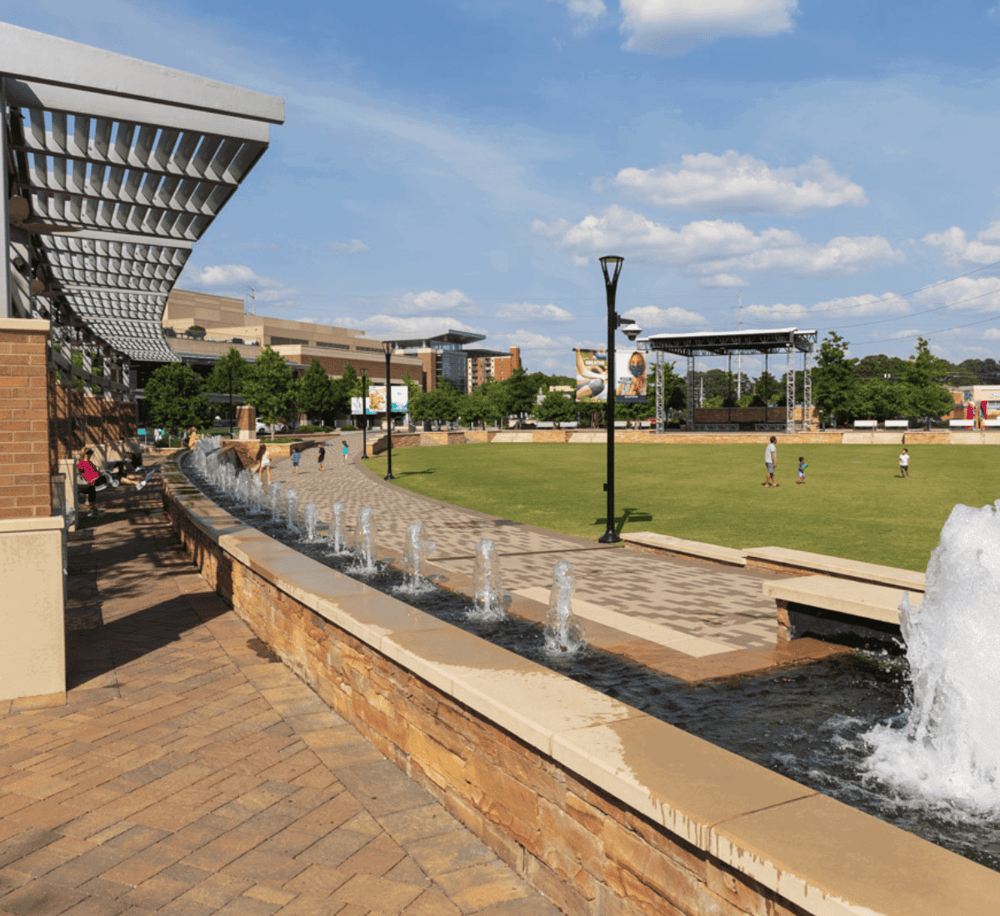 Relaxing urban park with fountains, open lawn, and cityscape background for outdoor recreation.