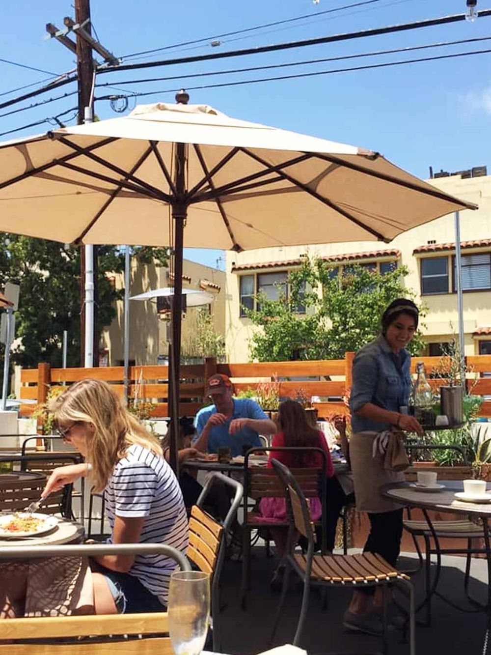 Outdoor restaurant dining with umbrellas and happy customers, perfect for food and casual gatherings.