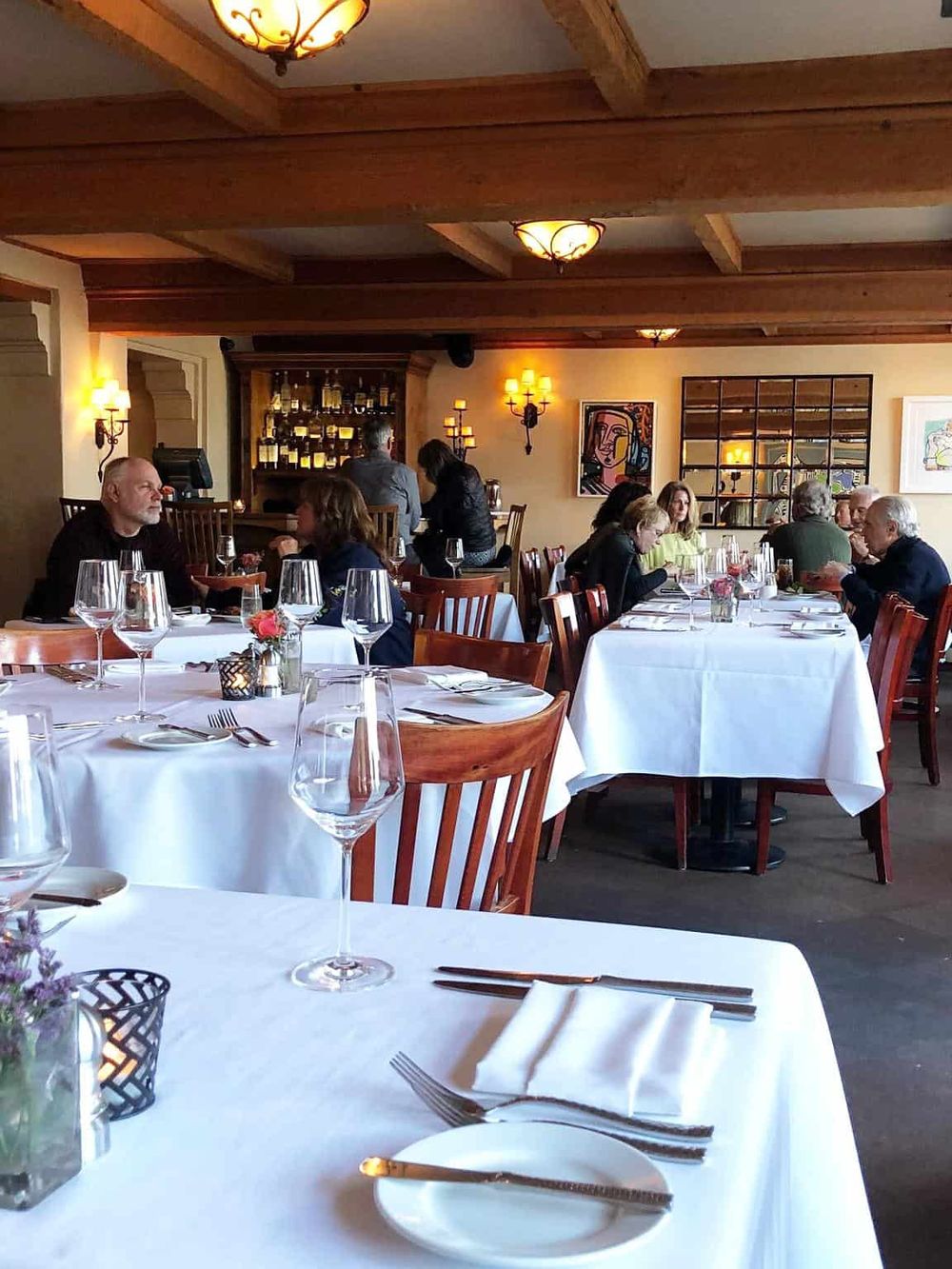 Elegant restaurant dining with white tablecloths, wine glasses, and warm ambient lighting.