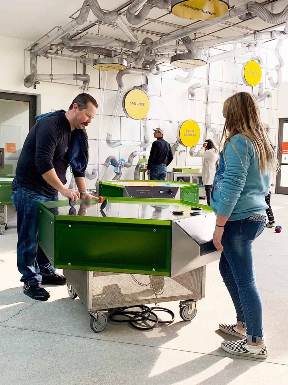 Indoor entertainment at QuestForDirections with people playing air hockey game.