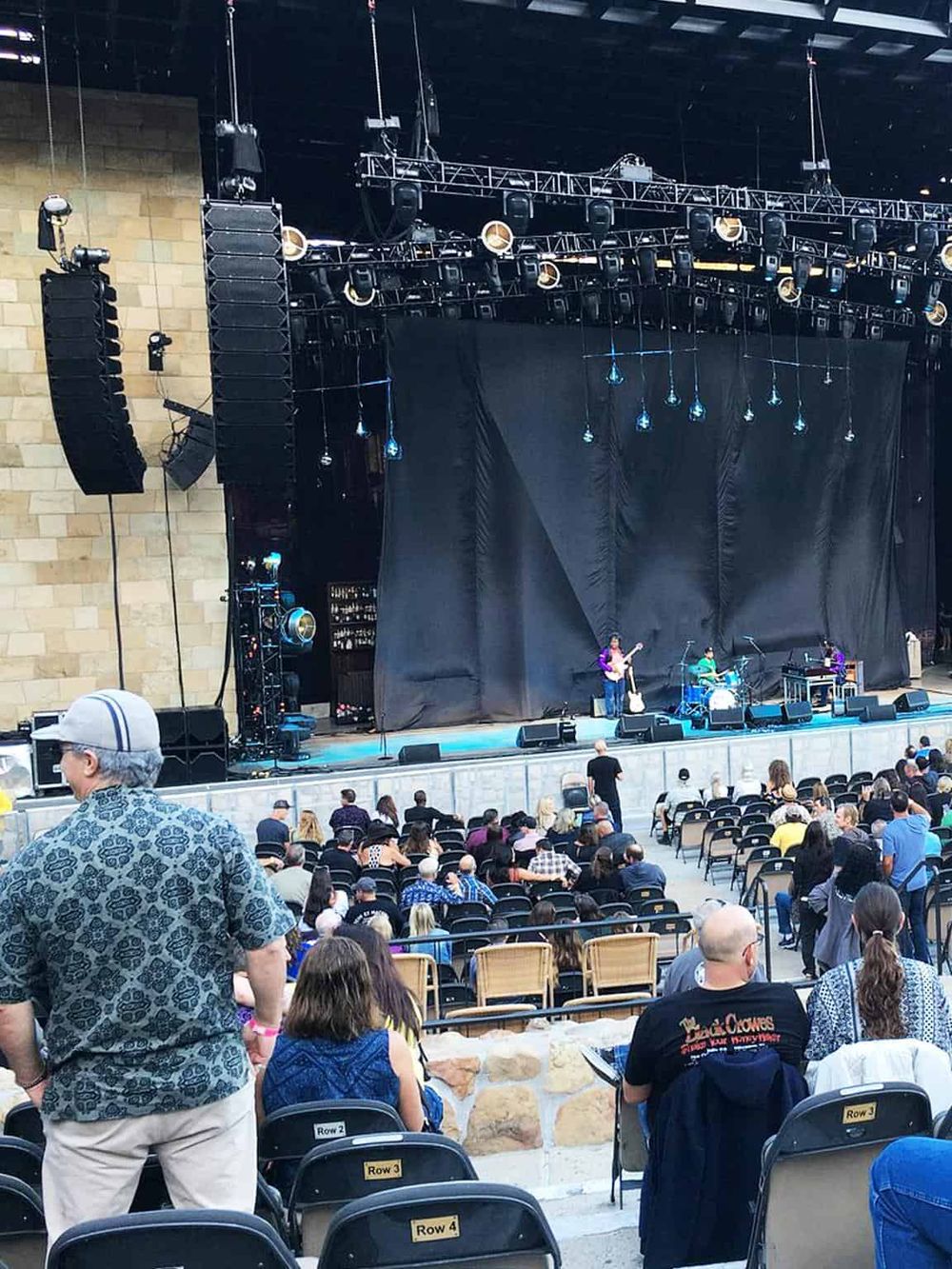 Live outdoor concert stage at QuestForDirections event, featuring band performing to an audience.