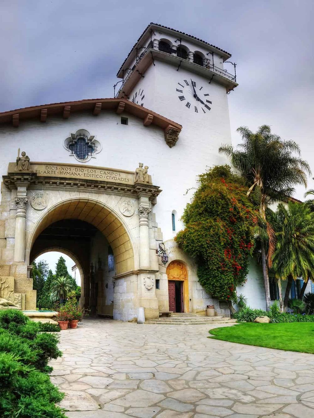 Historic Spanish-style clock tower with lush greenery and decorative architecture, located at QuestForDirections.