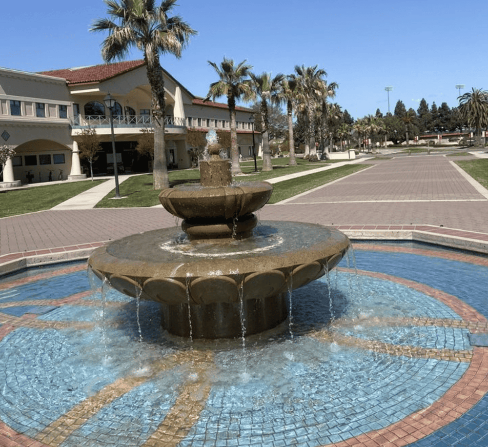 2023-10-03 17:23:57.391464 Water fountain in a scenic outdoor park setting with palm trees and pathways.