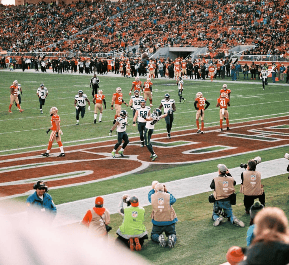 Exciting football game at Quest for Directions stadium with players, fans, and media coverage.