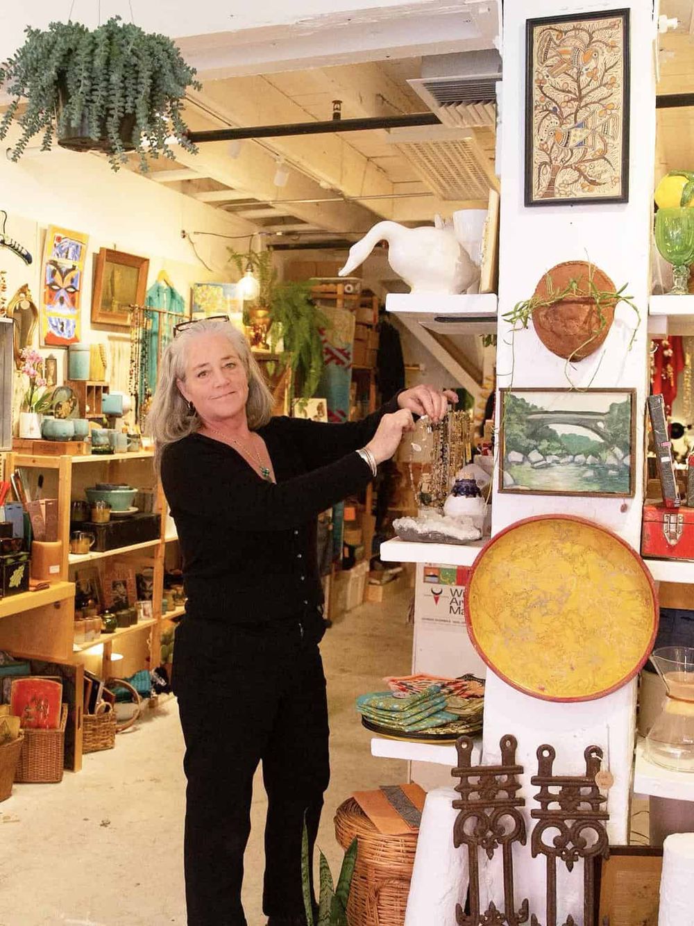 Colorful artisan shop with a woman browsing handmade decor and artwork in a cozy, eclectic setting.