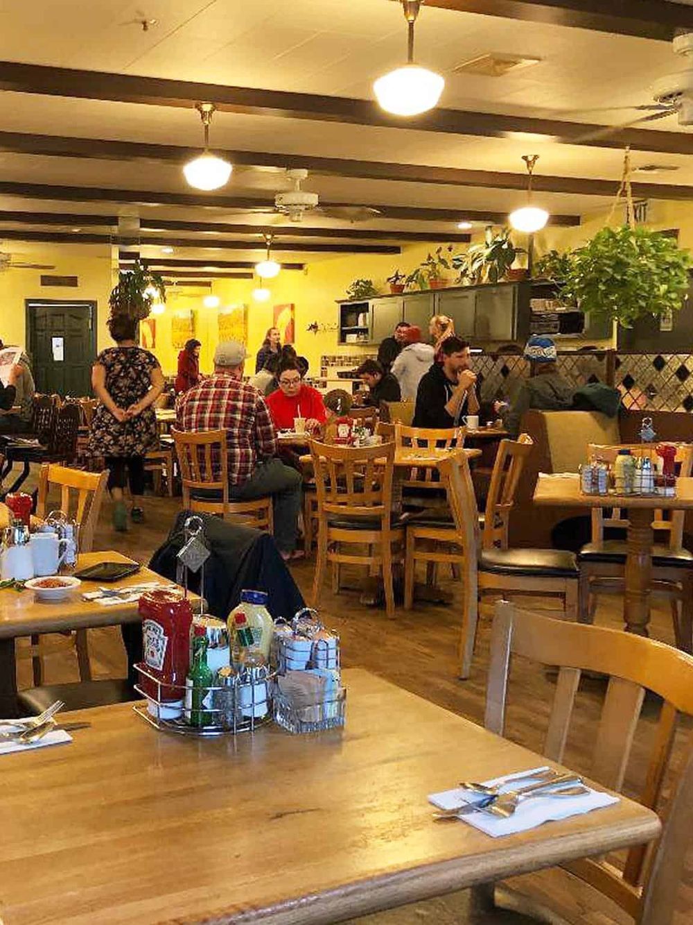 Cozy family restaurant interior with wooden tables, happy diners, warm lighting, and inviting atmosphere.