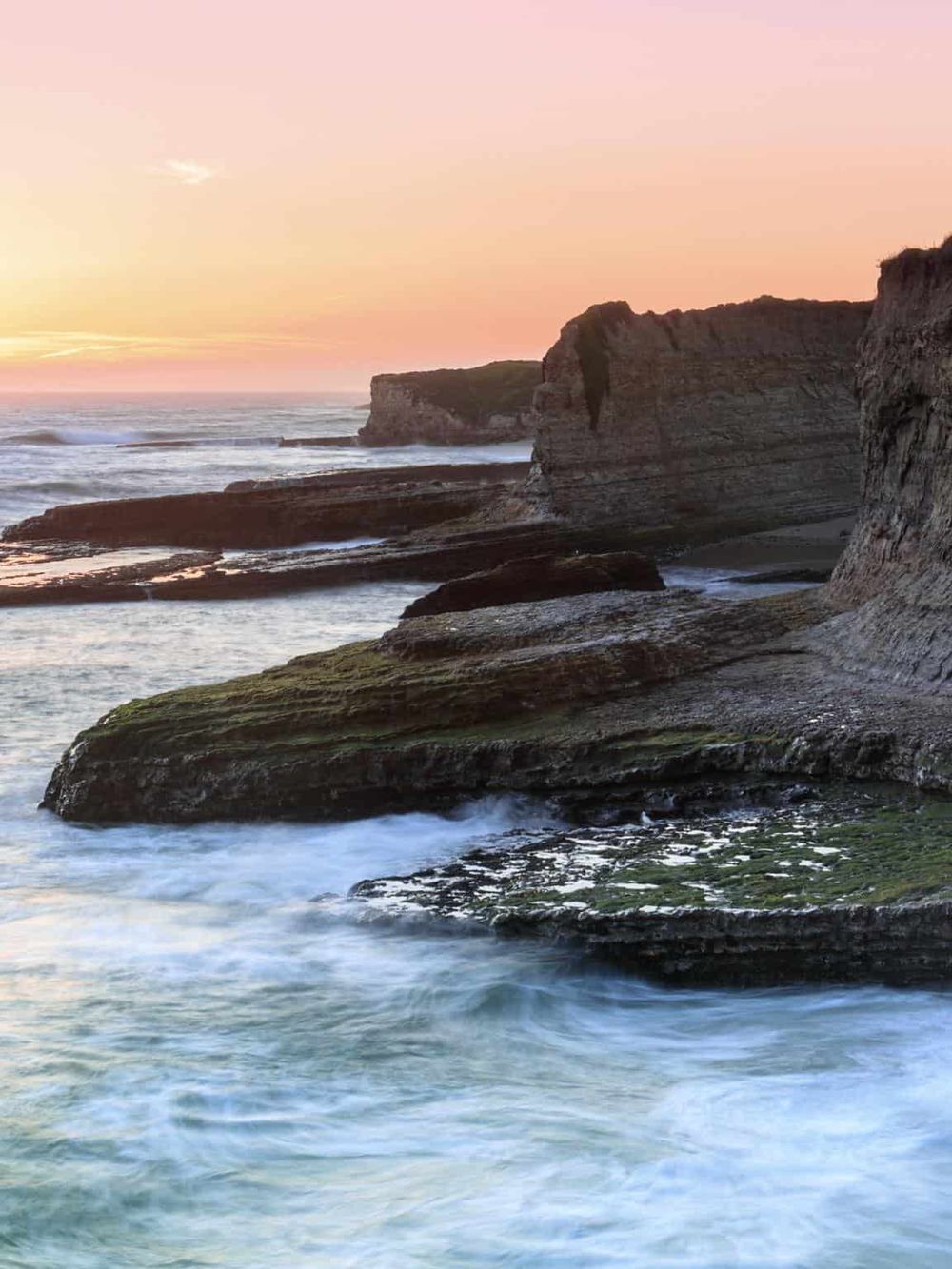 Vibrant sunset at rocky coastal cliffs, showcasing scenic ocean views and serene nature escape.