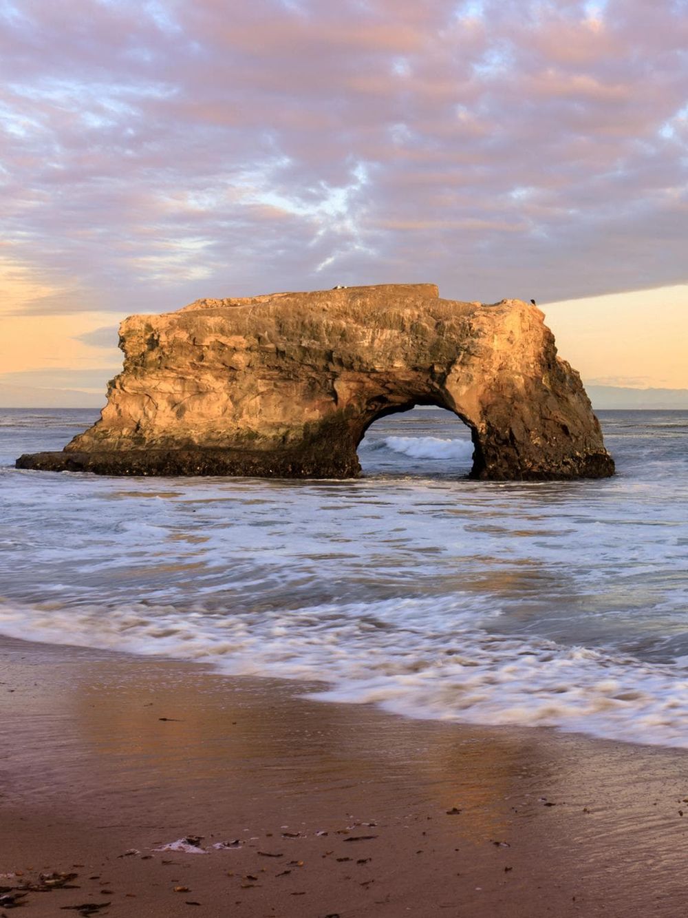 Majestic sea arch at sunset on the coast, geological formations, scenic ocean view.