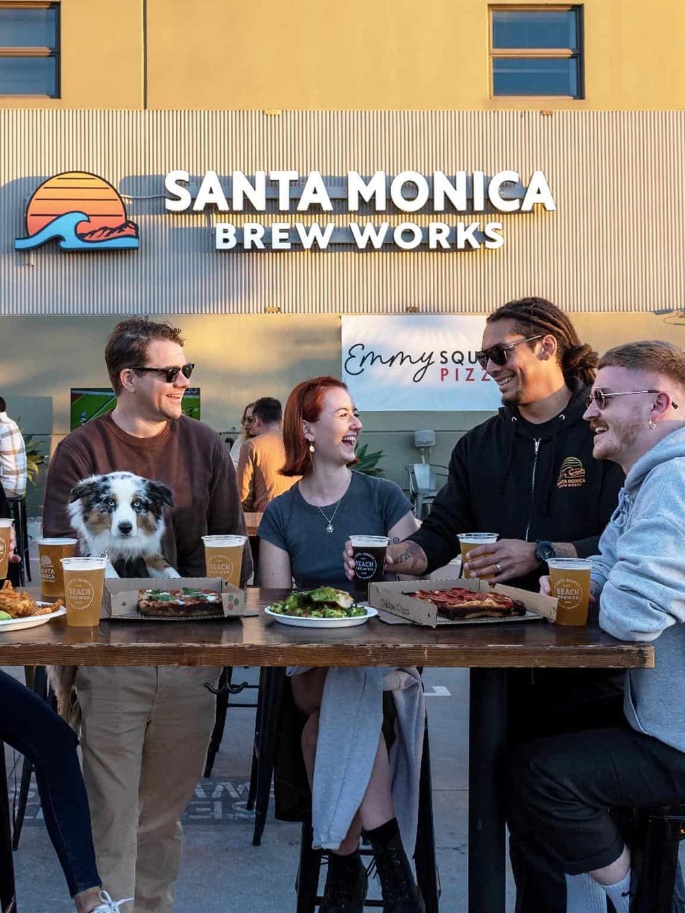 Vibrant outdoor scene at Santa Monica Brew Works with friends enjoying food and drinks.