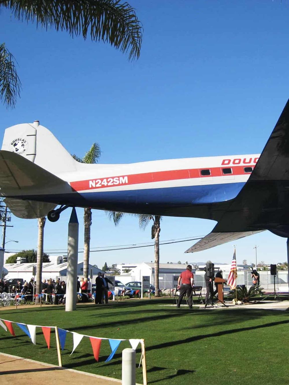 Historic airplane display at Quest For Directions event, California outdoor venue, people gathered under clear blue sky.
