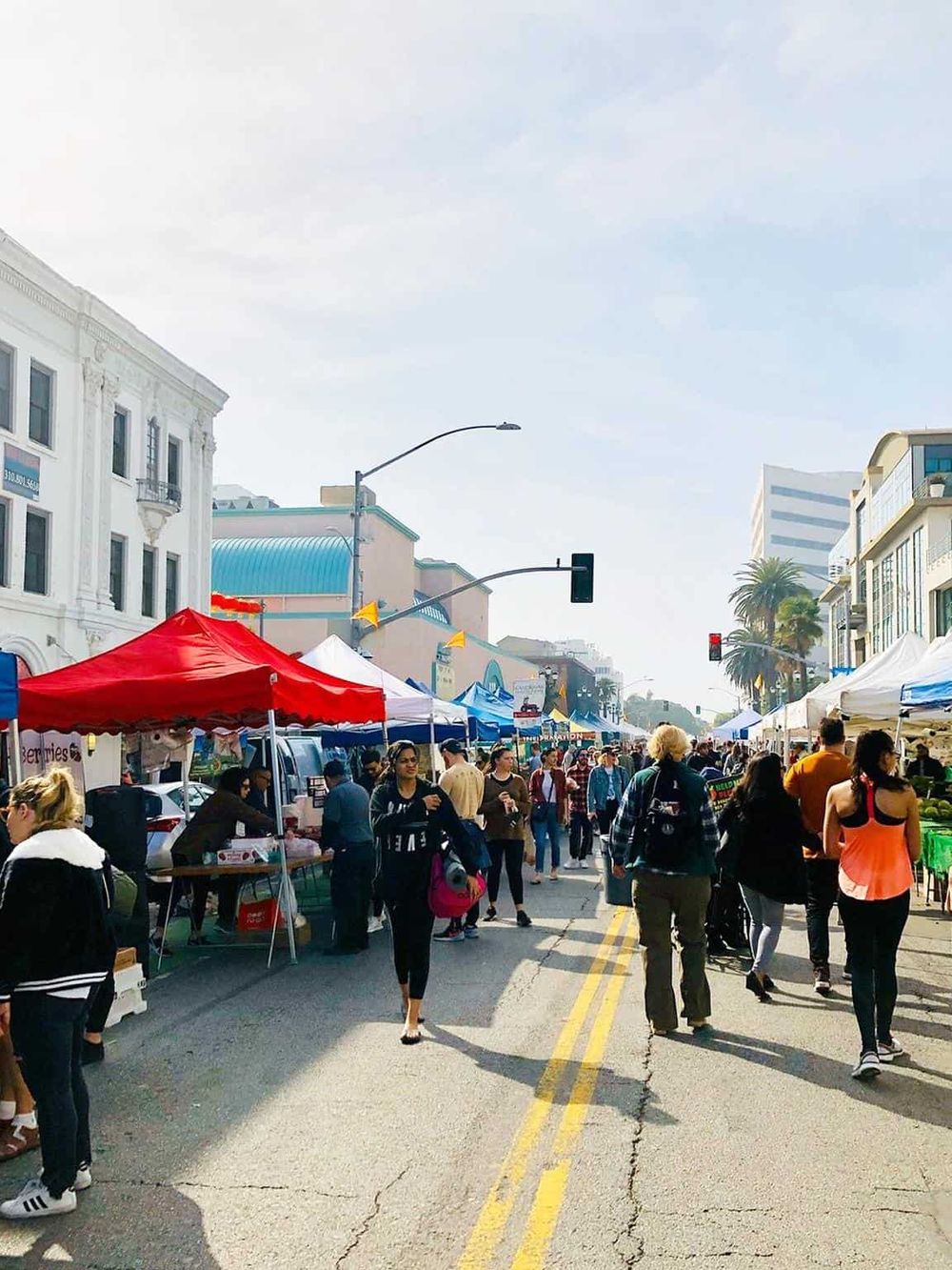 Vibrant outdoor street market with diverse shoppers, colorful stalls, and lively urban atmosphere.