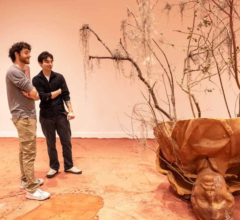 Striking art installation with sculpted face, dried branches, and earthy tones at QuestForDirections exhibit, showcasing innovative sculpture and design.