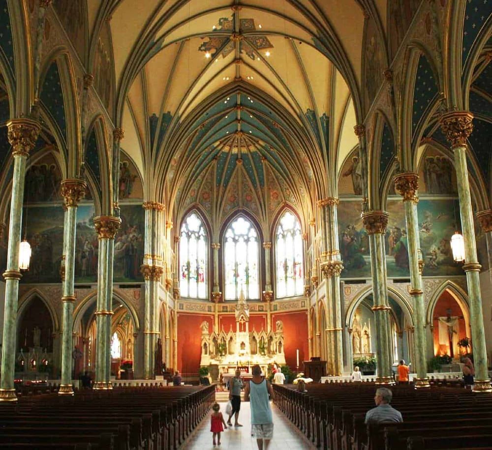 Opulent Gothic-style church interior with vaulted ceilings, ornate columns, and stained glass windows, ideal for religious tours and cultural exploration.