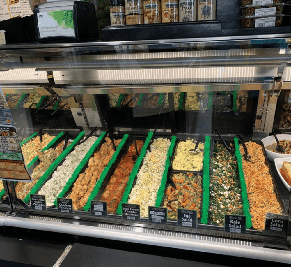 Fresh deli salads in a supermarket refrigerated display case, diverse options for healthy eating.