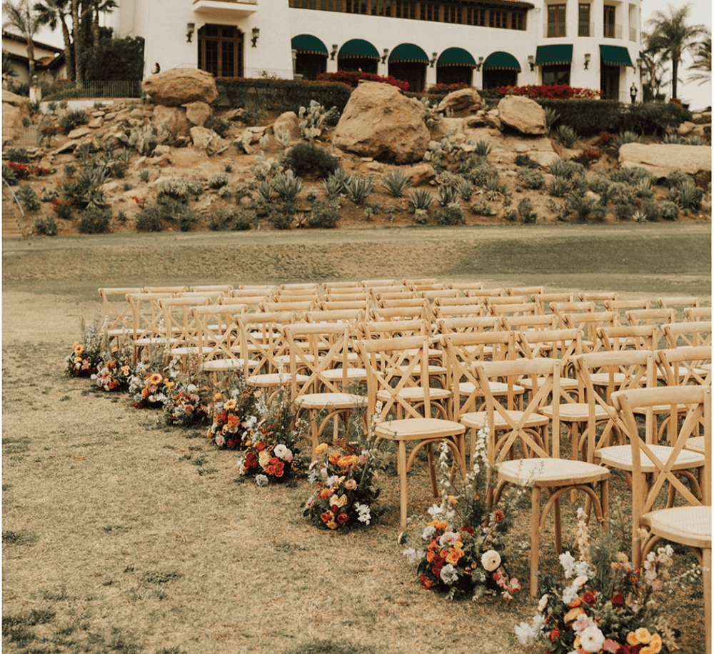 Elegant outdoor wedding ceremony setup with floral arrangements and wooden chairs at a scenic venue.