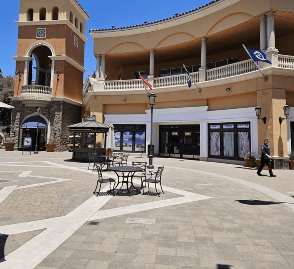Outdoor shopping plaza with cafes and flags, vibrant atmosphere, and clear pathways.